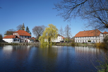 Fototapeta na wymiar Spiegelung von Häusern im Wasser an einem Teich in einem Ort