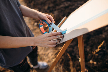 Crop artist attaching paper to easel in nature