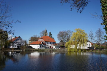 Fototapeta na wymiar Spiegelung von Häusern im Wasser an einem Teich in einem Ort