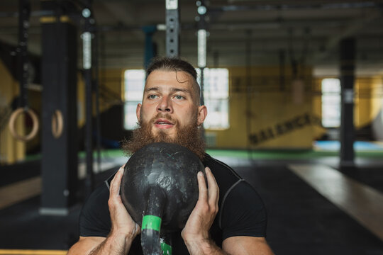 Strong and healthy man working out with a kettlebell , inside a crossfit gym.