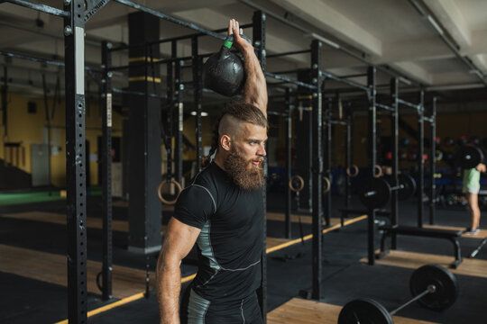 Strong and healthy man working out with a kettlebell , inside a crossfit gym.