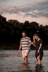 Couple in love walks on the water in the evening light. Splashing water.