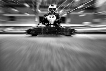 The man in a helmet in the go-kart moves on a karting track - obrazy, fototapety, plakaty