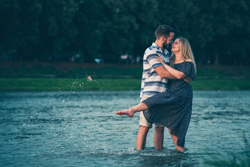 Couple in love walks on the water in the evening light. Splashing water.