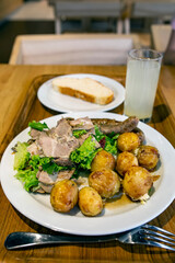 Young potato with meat and sausages. Plate with food on the table