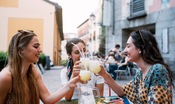 Happy Friends having lemonade drinks and toasting in a terrace o