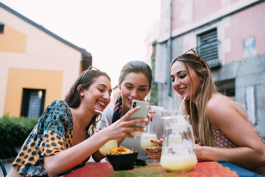 Happy Friends having lemonade drinks and using smartphone in a o