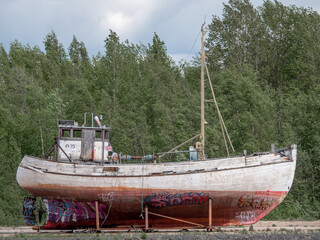 Old fishing ship in dry land sides sprayed with graffiti