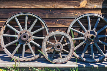 Obraz premium Vintage wooden cart wheels on the background of a wooden wall.