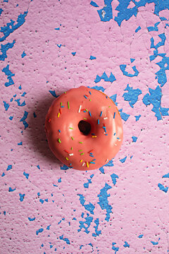 Bright iced glazed donuts on textured pink painted background