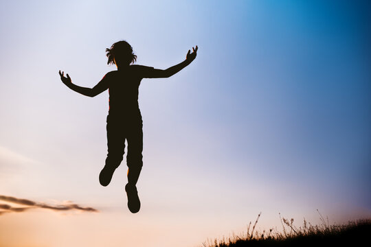Silhouette portrait of a girl jumping high in the air at sunset