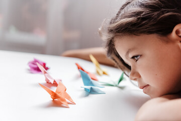 Girl looking at the origami butterflies she has just made