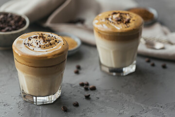 Dalgona whipped coffee, instant, cream, iced coffee. Cocktail with coffee, milk and ice cubes on grey background mockup. Trendy drink background with copy space for text.
