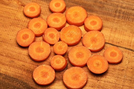 Cenouras picadas em rodelas, sobre taba de madeira.