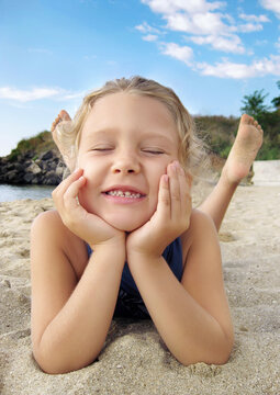Cute girl take the sun on a sandy beach and laughs