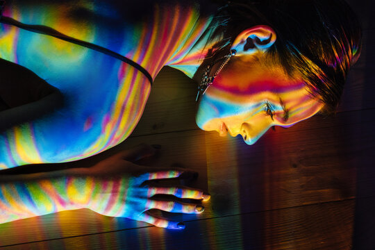 Model lying on floor under multicolored illumination