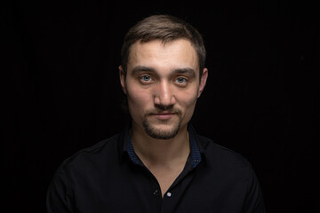 Obraz premium Closeup portrait of handsome man with a beard in black shirt. Isolated on black background