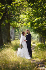 Young Bride and Groom couple in a summer garden. Tender holding each other. Redhead woman and blonde man with long hairs. Young family outdoor in nature. Love and tenderness