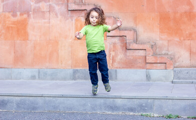 happy little long hair boy jumping in the park