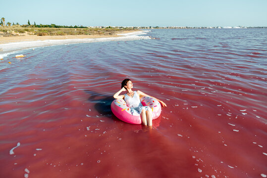 Beautiful woman lying on inflatable float mattress on pink sea