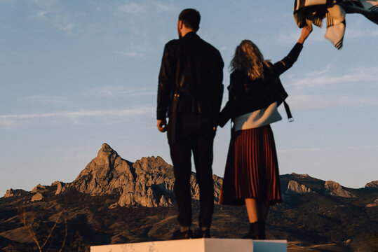 Back view of stylish couple standing together on mountain range background