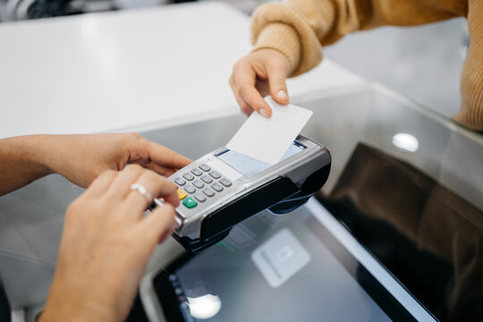 Detail of a client hands paying with a contactless card at a pharmacy