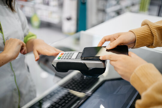 Detail of a client hands paying with the smartphone at a pharmacy