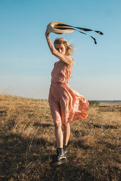 Female Fashion Model Wearing Silk Dress And Straw Hat Outdoors