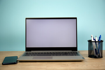 Laptop computer with a white screen on the desktop, blue background. Business and finance