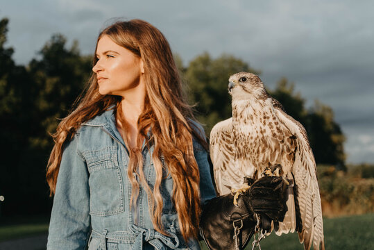 A woman in her twenties posing for a portrait with an owl in a forest