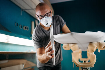 Surf shaper making a board with a sandpaper