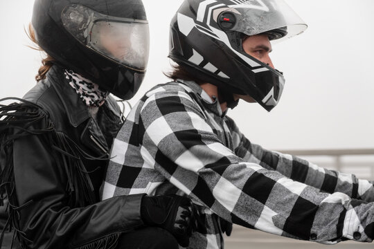 Attractive couple riding vintage motorcycle across the bridge over river, foggy weather.