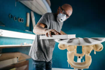 Surf shaper making a board with a sandpaper