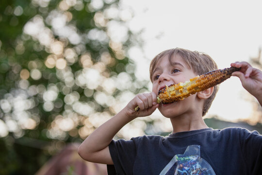 4 year old boy eating baked corn