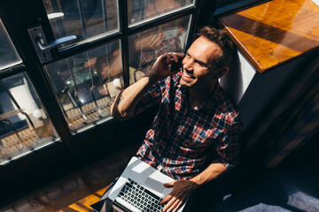 Young man having a conversation on cellphone while looking through the window