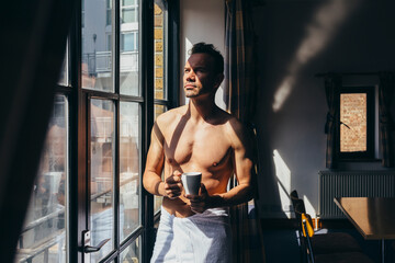 Adult man enjoying the sun rays sitting besides the window in the morning