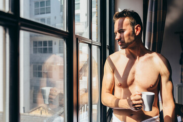 Adult man enjoying the sun rays sitting besides the window in the morning