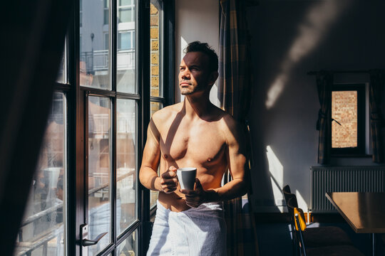 Adult man enjoying the sun rays sitting besides the window in the morning