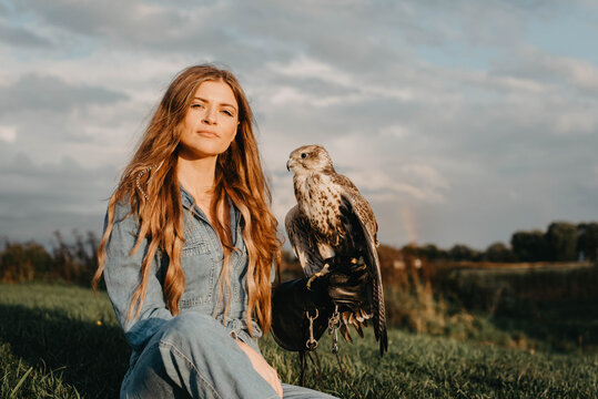 A woman in her twenties posing for a portrait with an owl in a forest