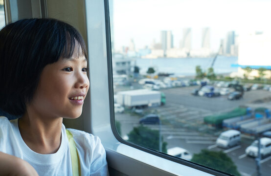Cute Asian girl looking through the window of the city.