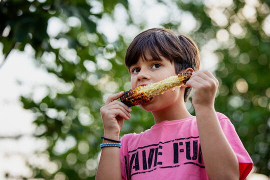 8 year old boy eating baked corn