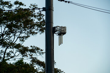 Transmission station attached to a voltage pole. Blue sky in background.