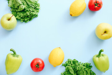 Various fresh vegetables and fruits on blue background. Ingredients for cooking. Frame from tomatoes, peppers, lemons, apple and lettuce