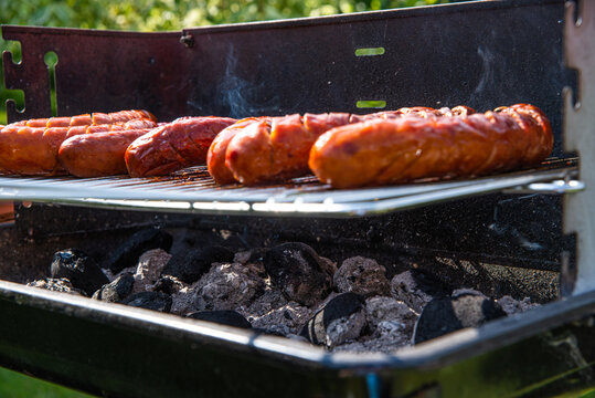 Grilling sausages. The concept of resting in the fresh air, frying sausages on the grill. Arranged sausages, barbecue.