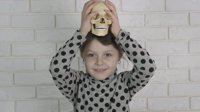Day of death with child. A little girl plays with a human skull.
