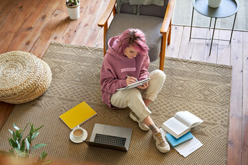 Hipster teen girl school college student pink hair studying online on laptop writing notes video...