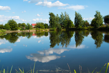 Lake in the village. The sky is reflected in the water. Summer