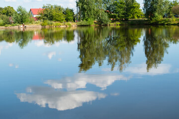 Lake in the village. The sky is reflected in the water. Summer