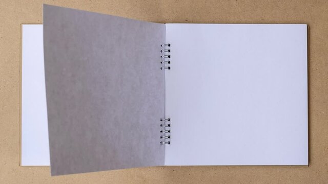4K UHD Stop motion book animation open white blank page for writing on wooden background.