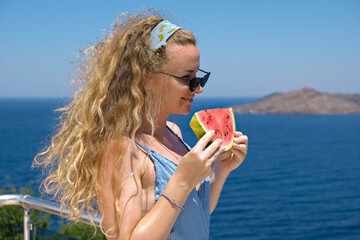 beautiful woman with a slice of watermelon wearing swimsuit with sea view holiday summer